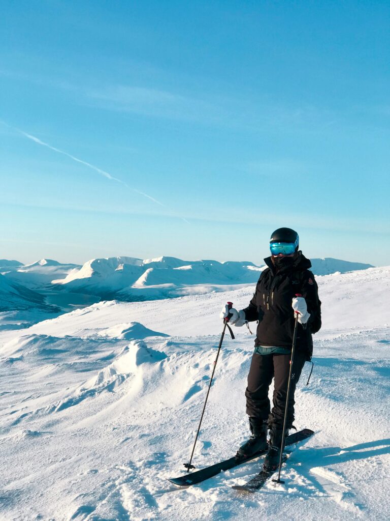 A skier enjoys the snow-covered mountains of Norway under a bright, clear sky.